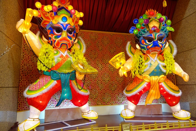 two large asian figurines in colorful clothing