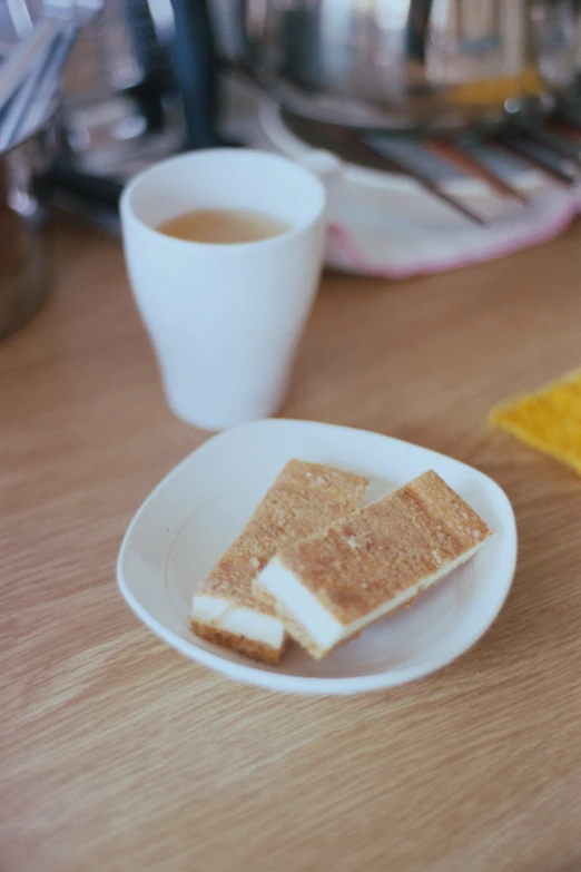 toasted slices of food sit on a plate next to a cup of coffee