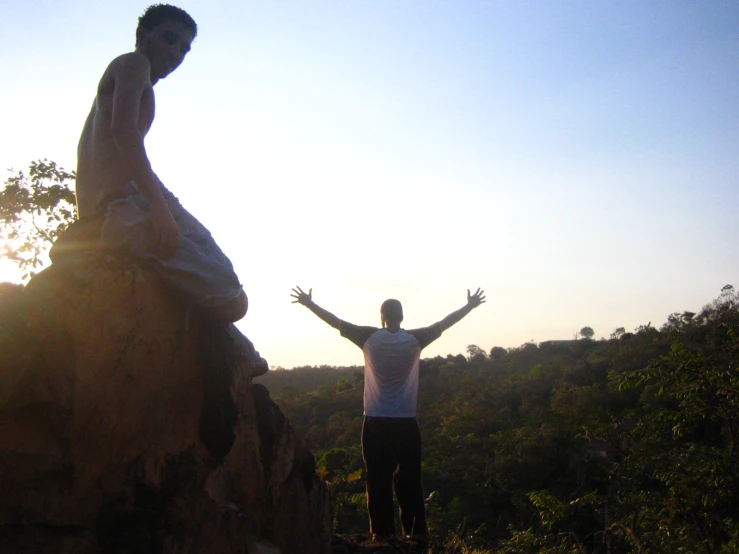 a young man raises his arms with both hands in the air next to a statue