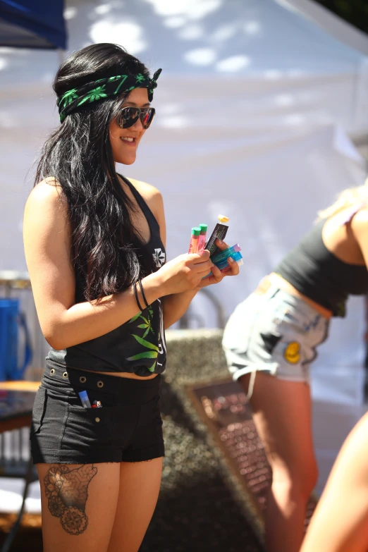 a beautiful young woman standing next to another girl holding a cup