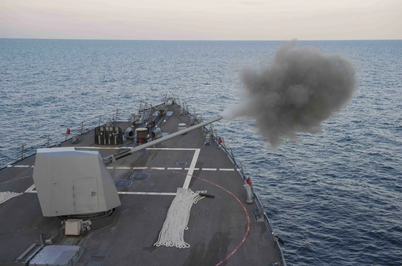 black smoke is dropping from the stern of a navy ship