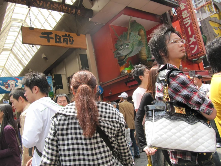 a woman in plaid shirt walking down street next to buildings