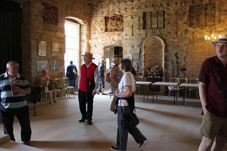 the people are standing in the large stone room