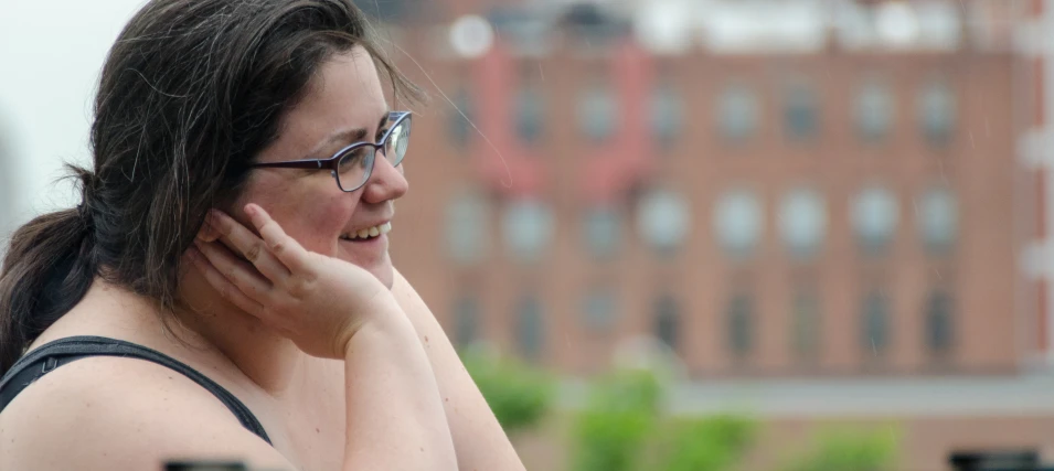 woman in glasses and black shirt smiling while talking on her cell phone