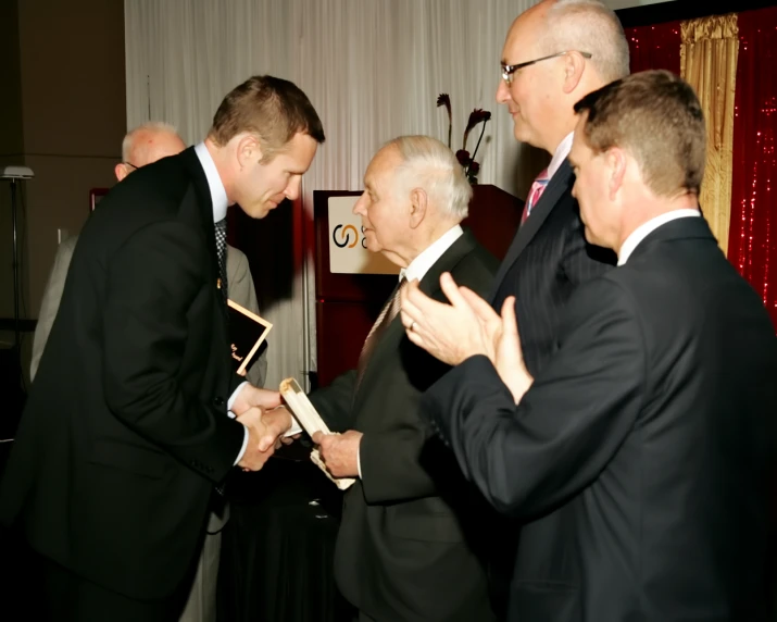 a group of men in suits looking at an award