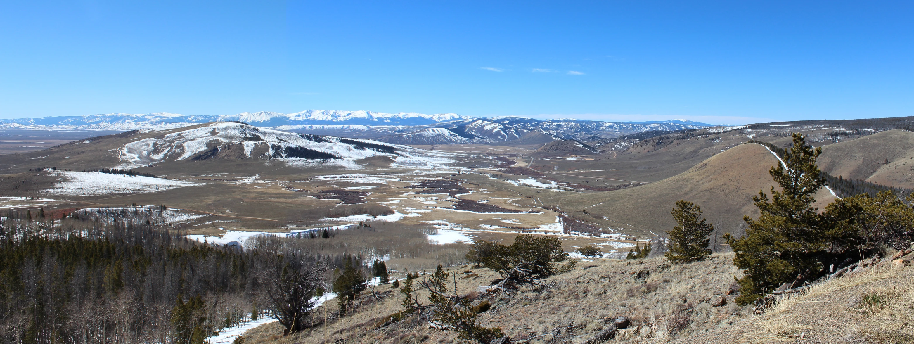 the view from the top of a mountain shows an expansive range and several forested areas