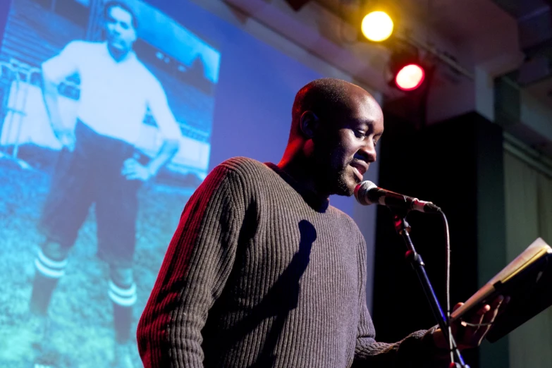 the man is standing behind a microphone while giving a presentation