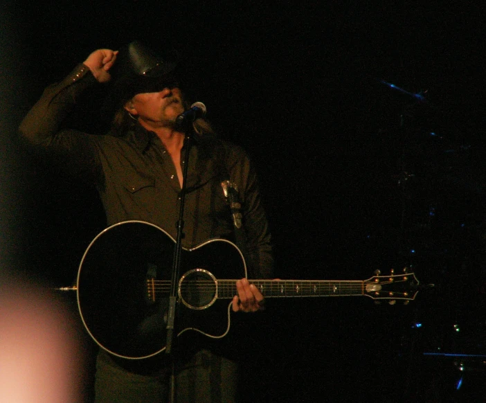 a man is singing into a microphone and playing guitar