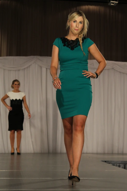 woman standing in front of a fashion runway, in green dress