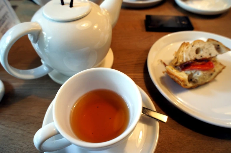 a white cup of tea next to two slices of toast