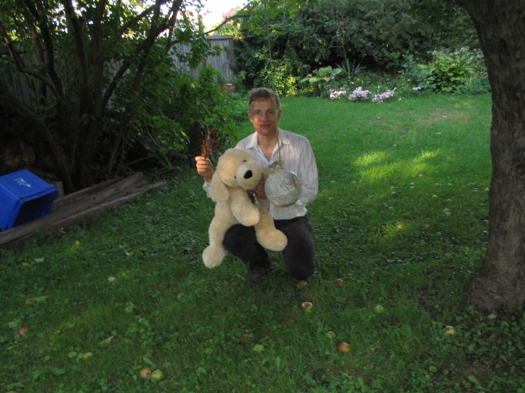 a man holding a teddy bear in a yard