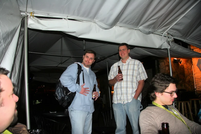 three men are talking outside in a tent