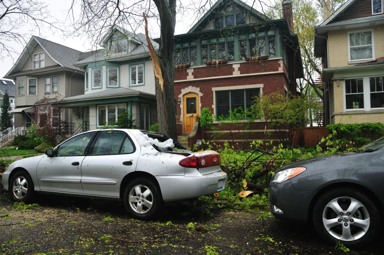 a car is parked by a house that's up against the tree