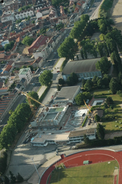 an aerial view of a stadium, tracks and buildings