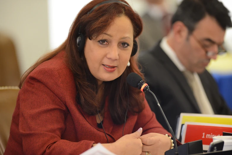 a woman in headphones and a man in suit sitting behind her