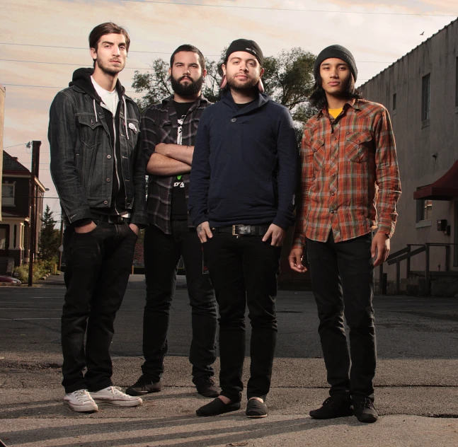 five men are standing together on a sidewalk