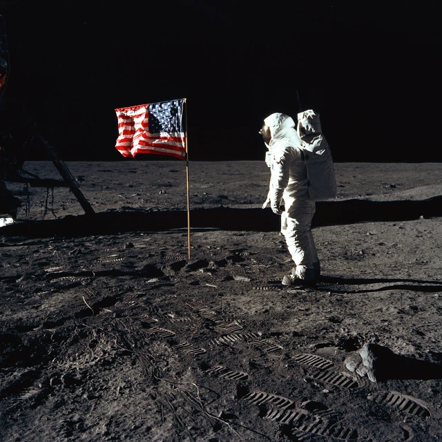 an astronaut on the moon walking next to a flag