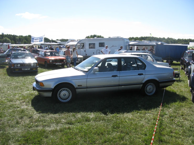 cars in an open field with people near the vehicles