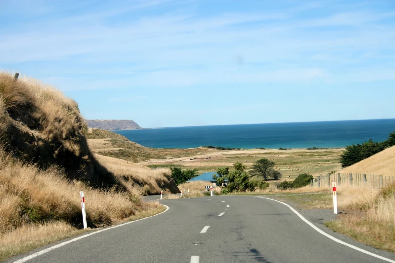 an empty road that leads up to the ocean