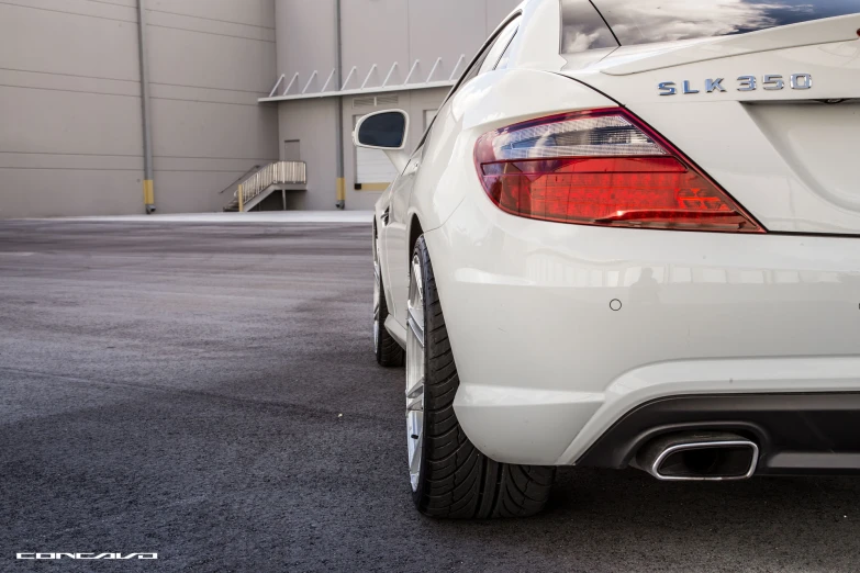 the rear end of a white car parked in a parking lot