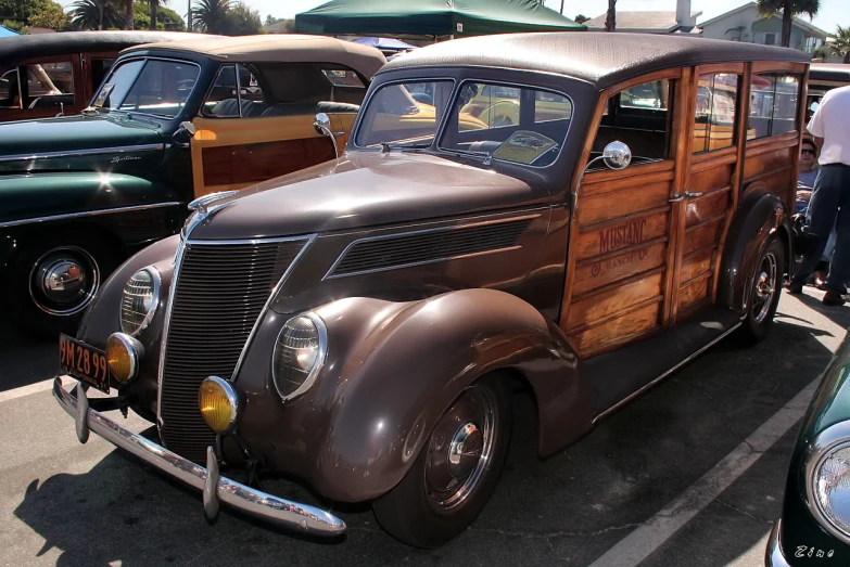 the old wooden car is parked beside other vintage cars