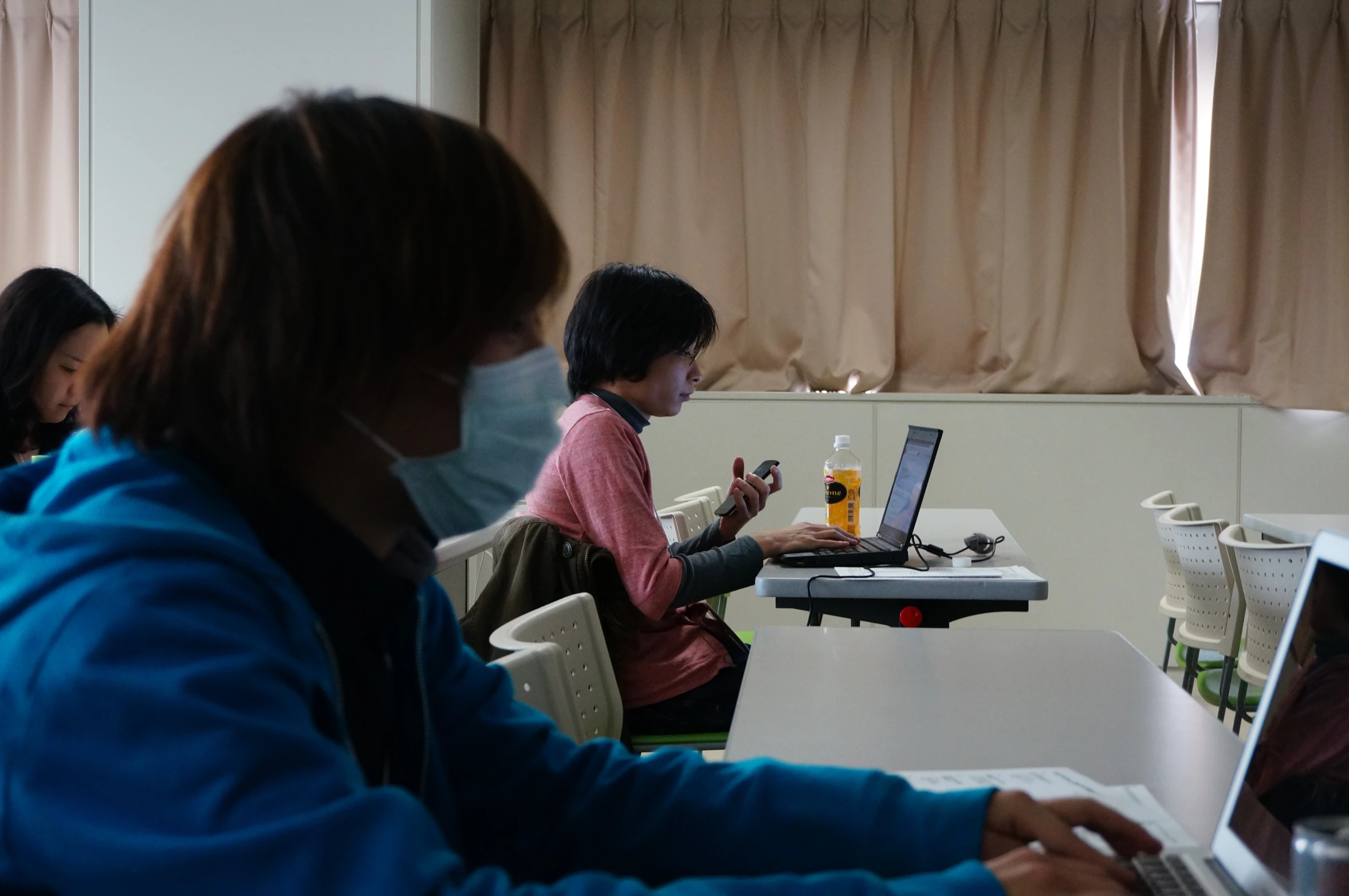 two women sitting at a table while working on their laptops