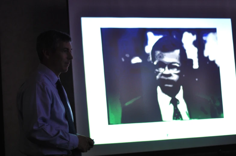 a man is walking by a large projection of a person