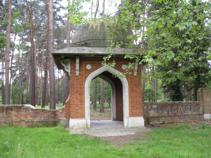 an old brick structure surrounded by trees with a stone fence