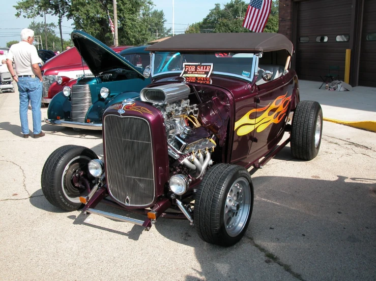 an older style  rod vehicle parked with its hood up