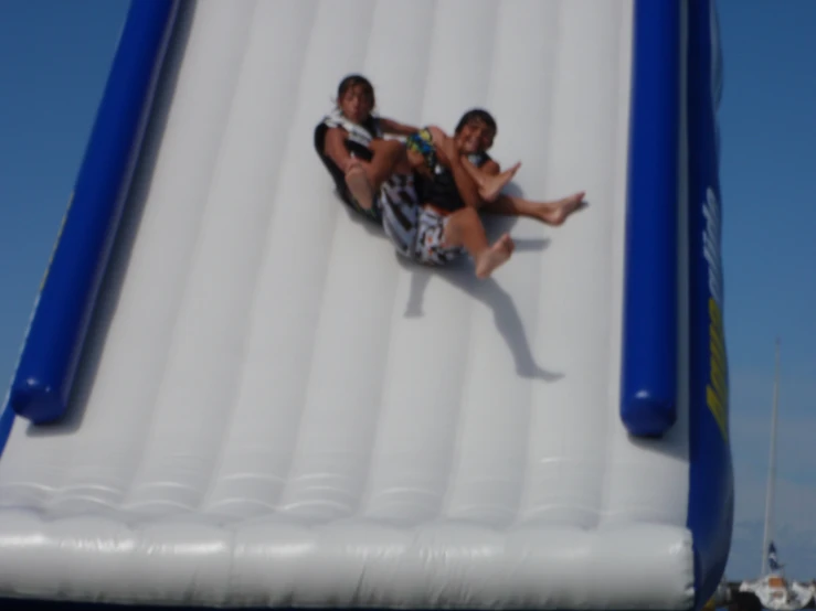 two people are laying down on the water slide