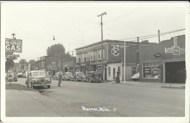 old time picture of car driving by shopfronts