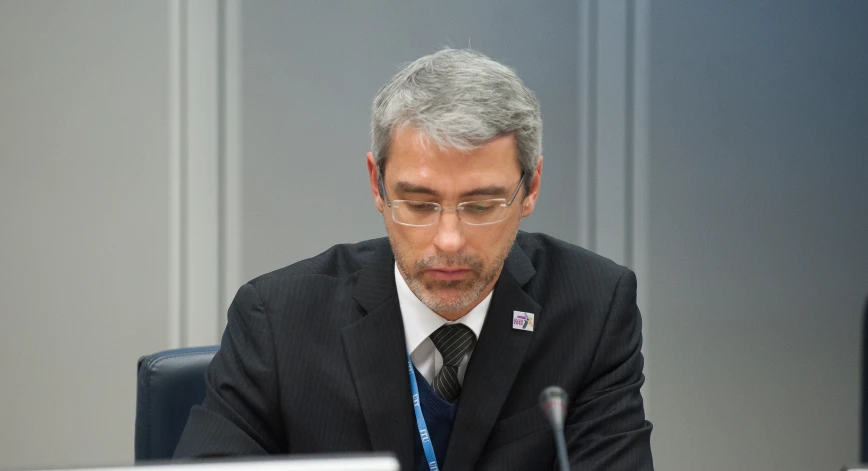 a man with a tie sits at a table while looking at a computer