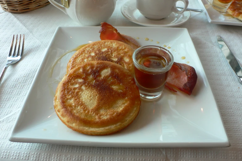 two breakfast pancakes sitting on a plate with a cup of coffee