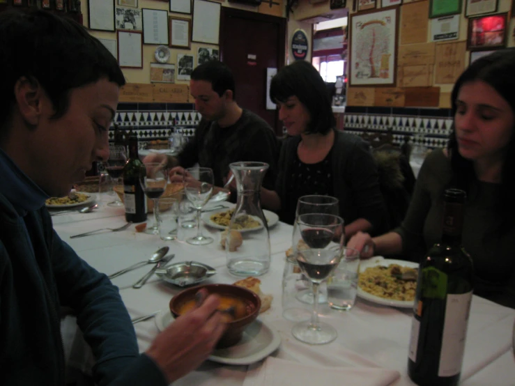 group of people sitting at a table with food and wine