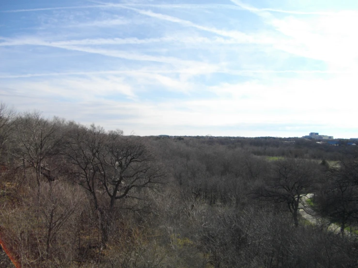 an overview of a field and trees under a cloudy blue sky