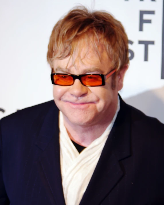 a man wearing red glasses smiles for the camera