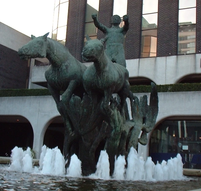 this is the entrance to a building with a fountain of water and horses on the outside