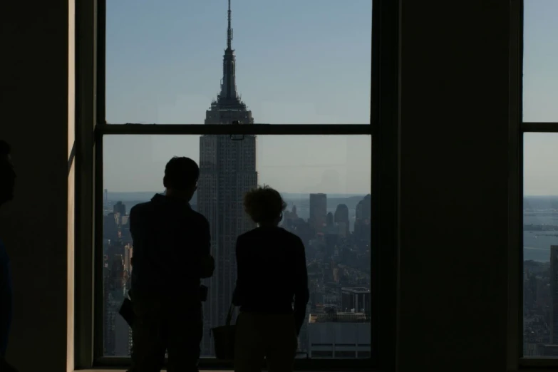 two boys looking out a window overlooking empire state