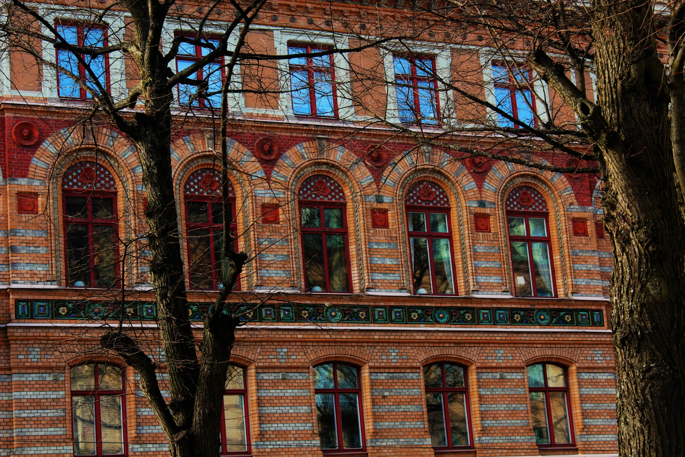 an old brick building with many windows and some trees in front of it