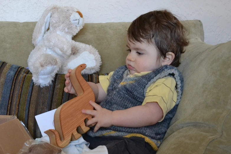 a  holding a wooden toy on top of a couch