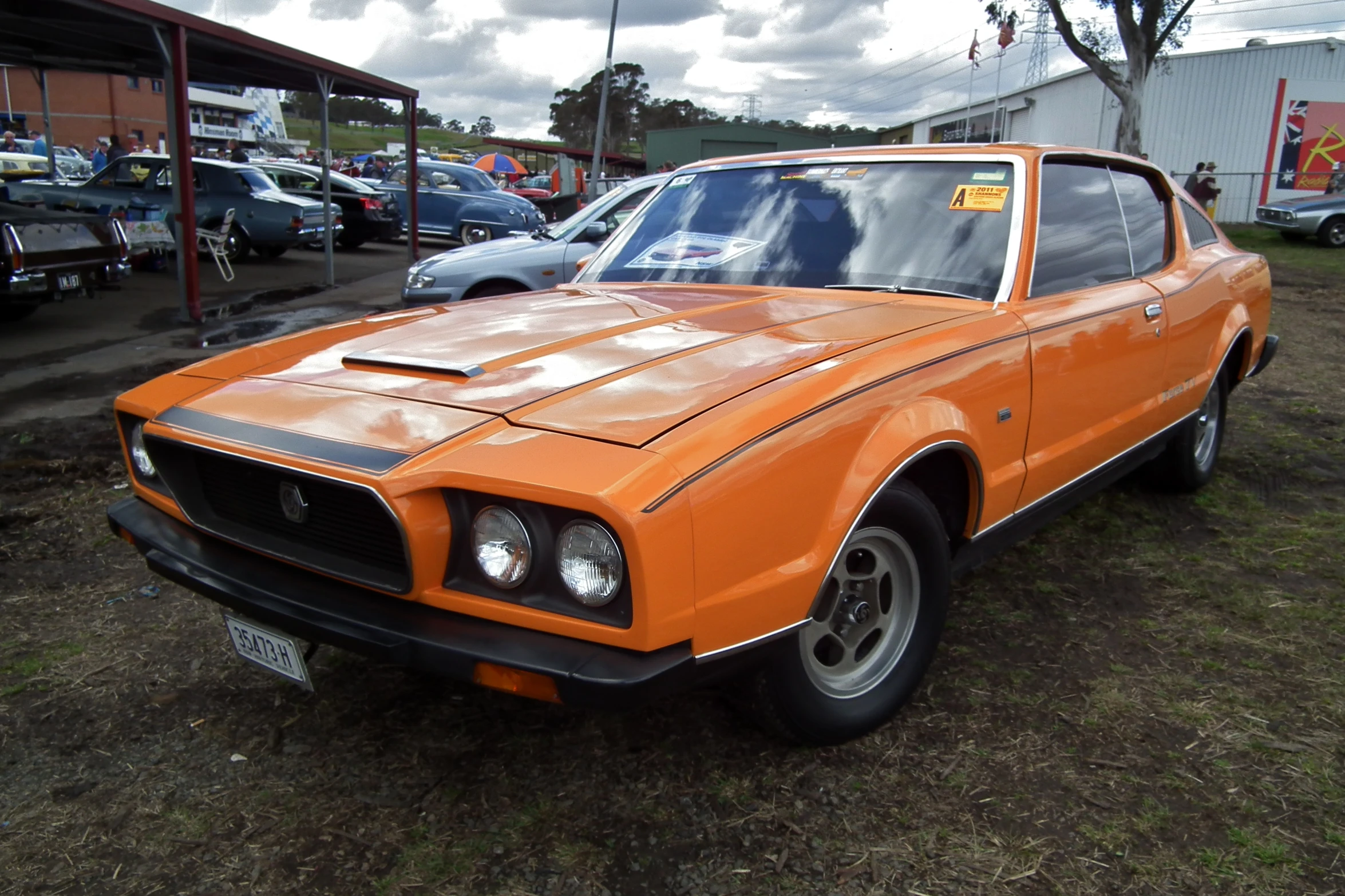 an orange car is parked in front of some other cars