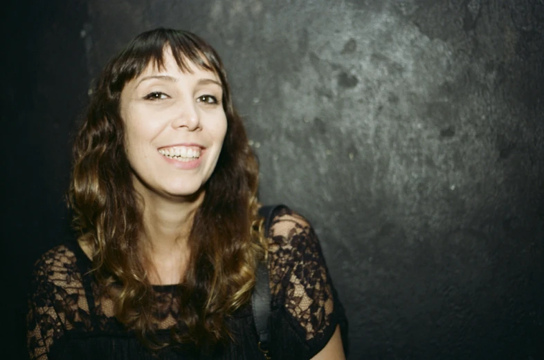 the smiling woman has dark hair and a lace sleeve