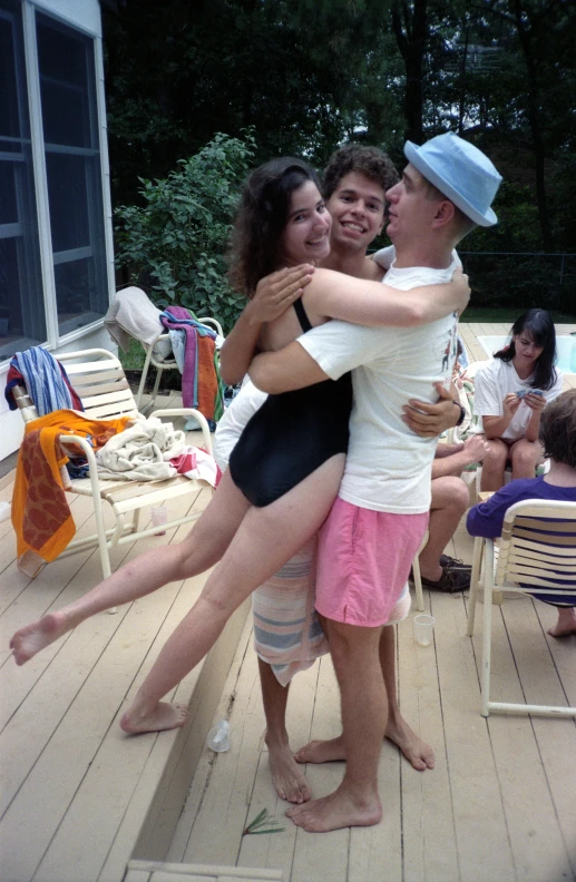 a group of young people hug on a deck