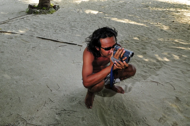 a man taking a po with his cell phone on the beach