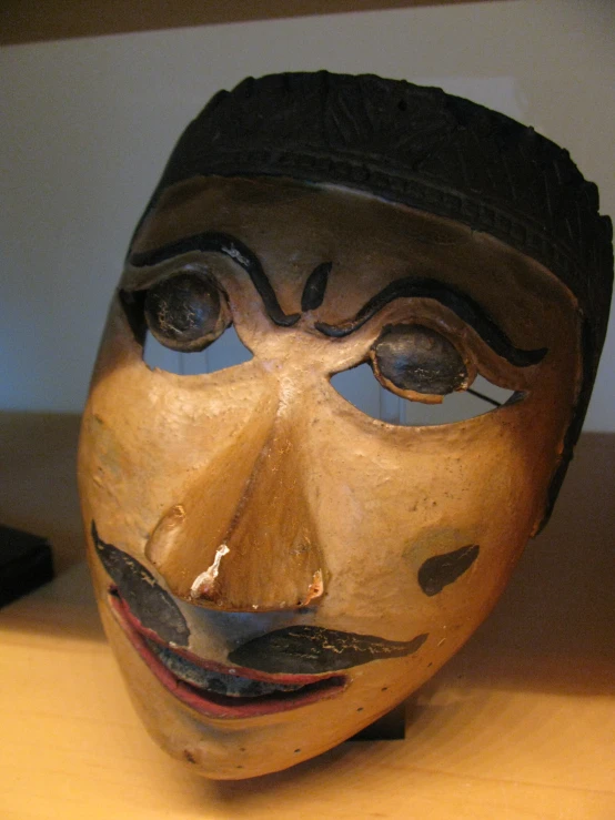 a wooden head on a table next to a remote control