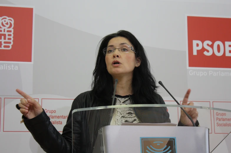 a woman with glasses on talking into a microphone