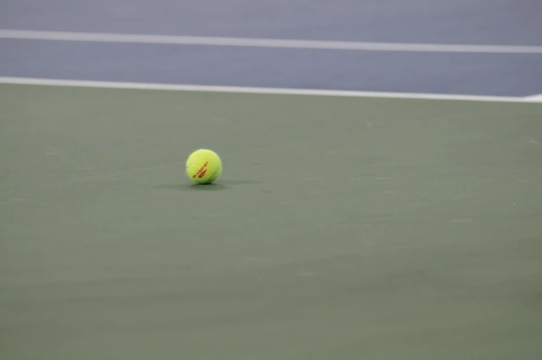 a tennis ball laying on a court during the day