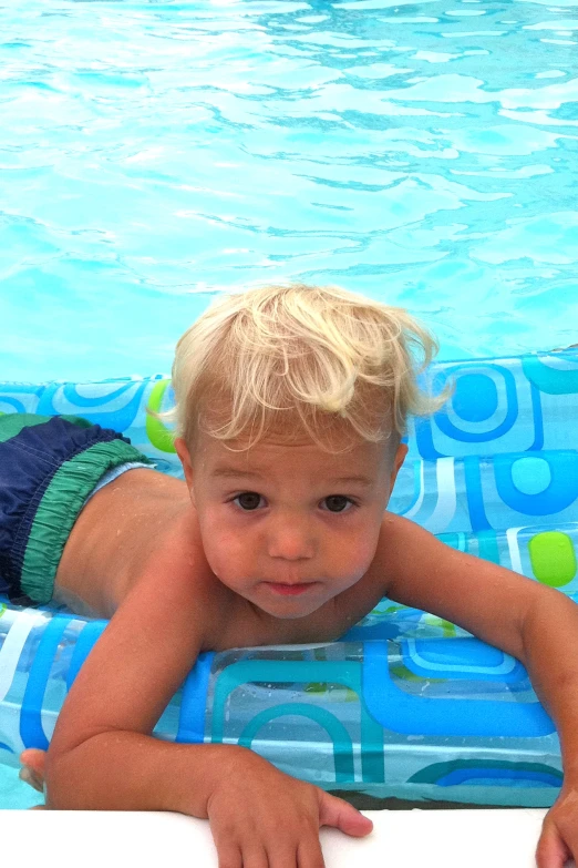 a little boy that is laying down on a pool