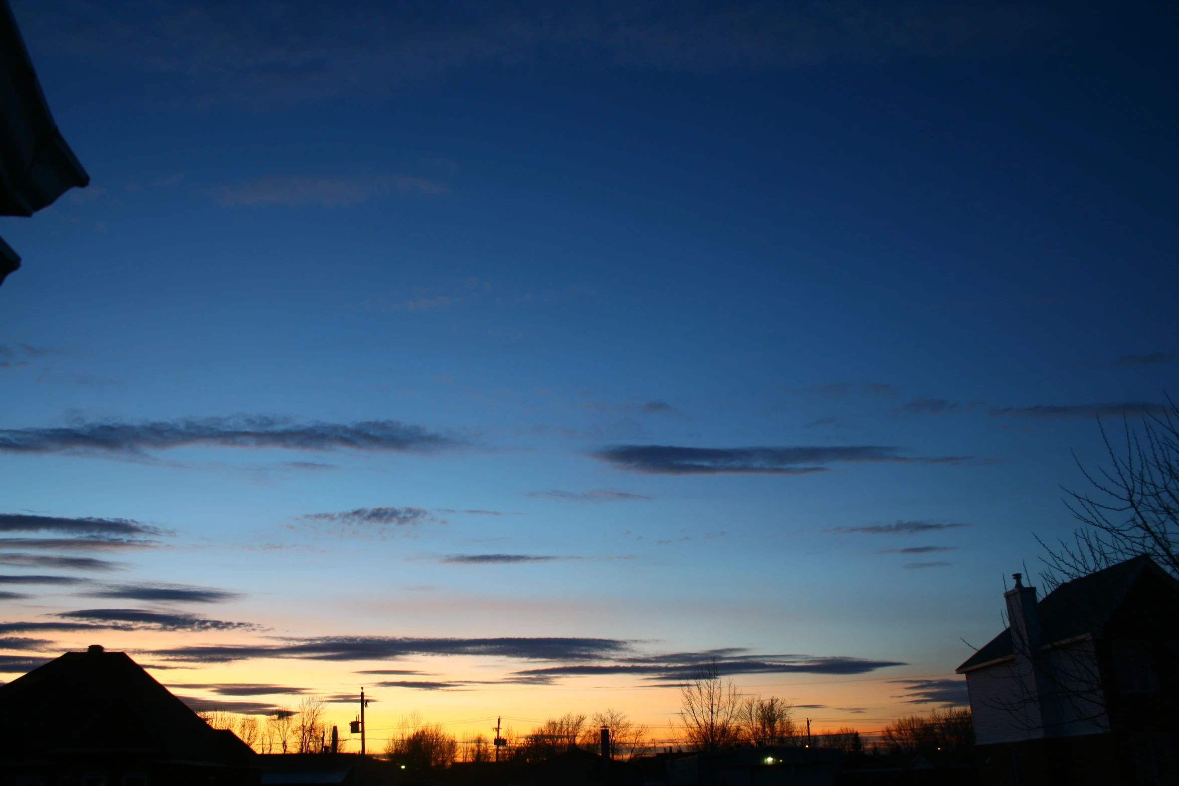 the sun sets behind several buildings with a street light on