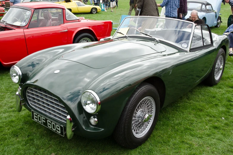 two vintage sports cars on display in grass